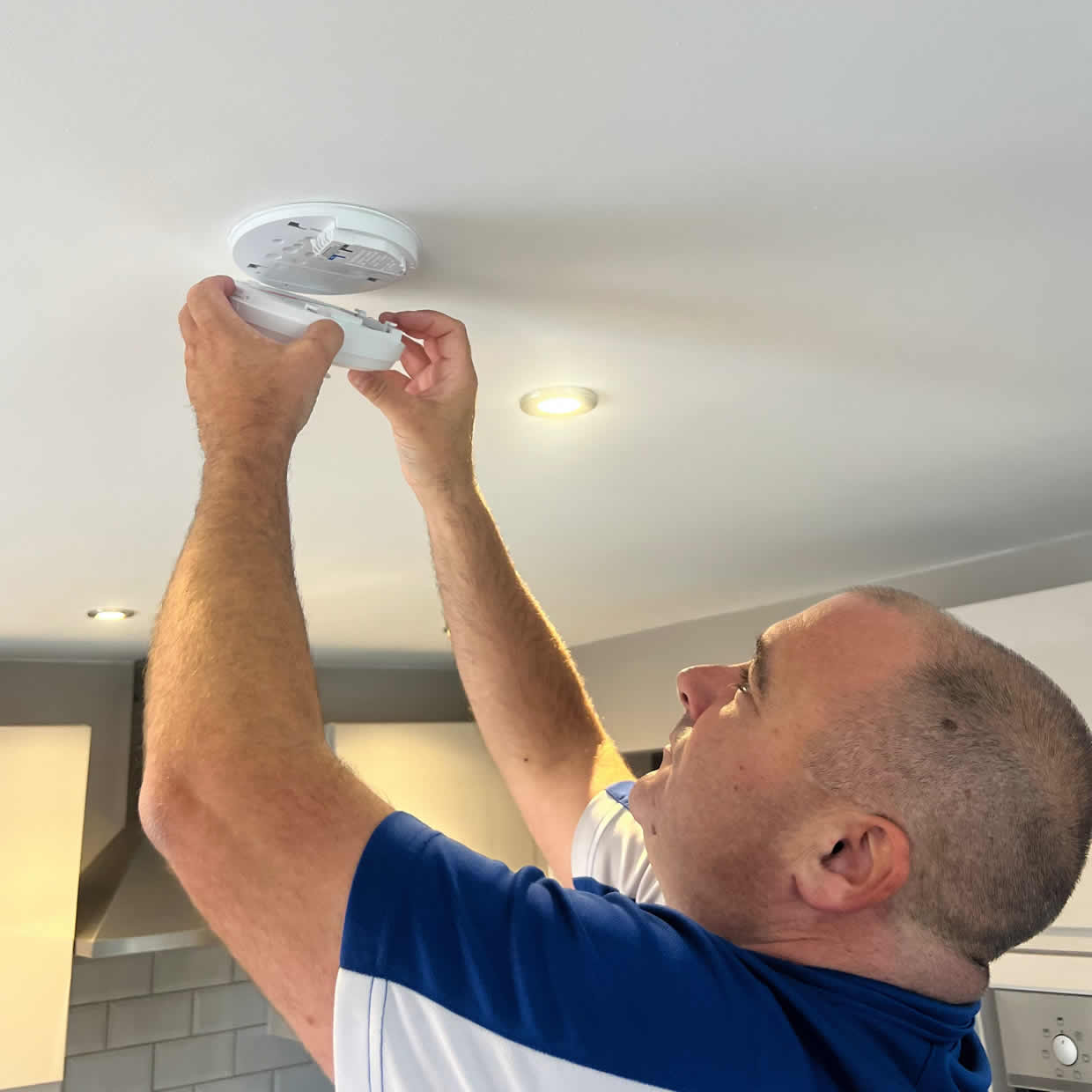 Smoke alarm installer fitting an alarm in a Blackpool property